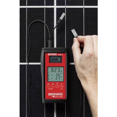 Egy kéz hőmérőt tart egy napelem előtt, amely 36°C-ot mutat egy 27°C-os környezeti hőmérsékletnél.