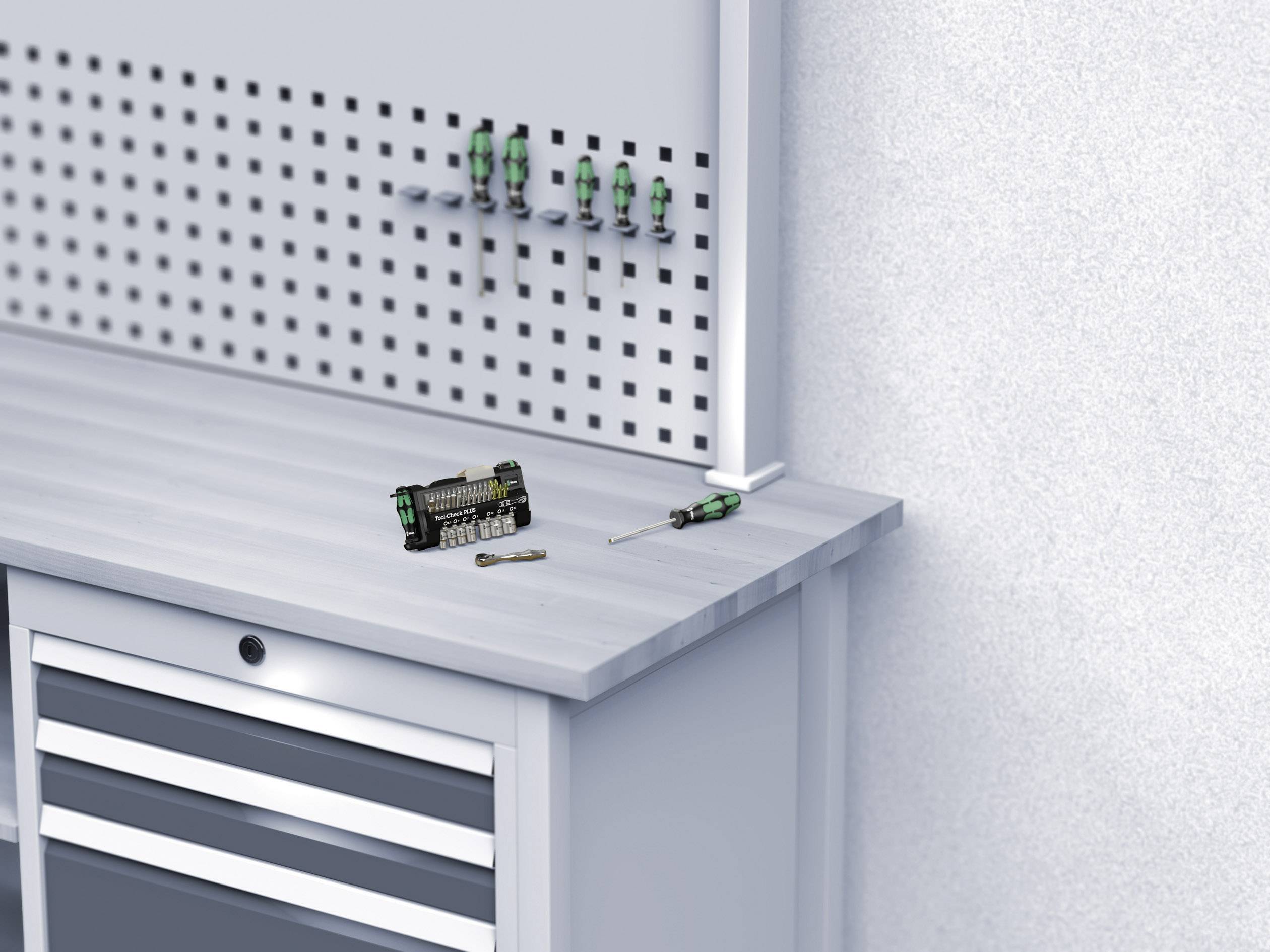 Munkaasztal csavarhúzókkal és bit-készlettel a felületén, néhány csavarhúzó a fölötte lévő fali tartón lóg.