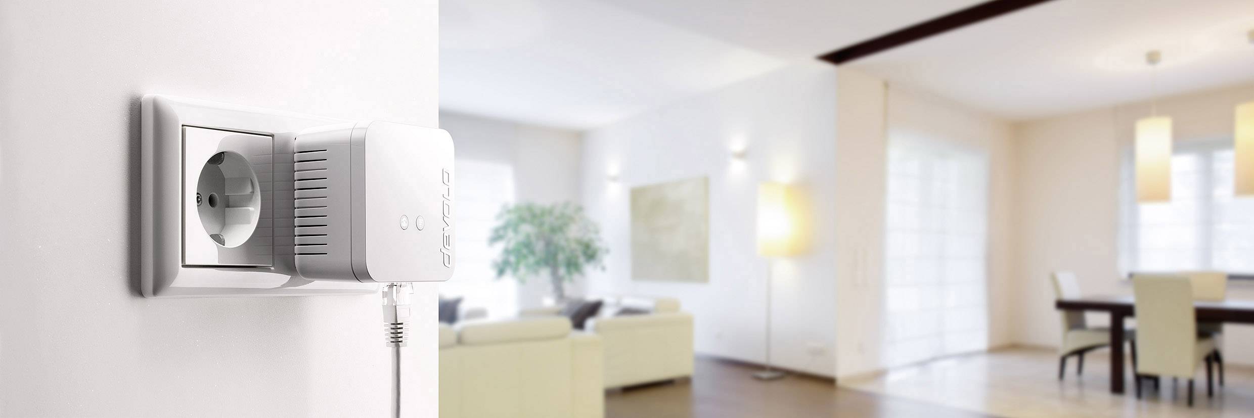 Egy fehér WIFI-adapter egy konnektorban egy modern nappaliban, világos falakkal és bútorokkal a háttérben.