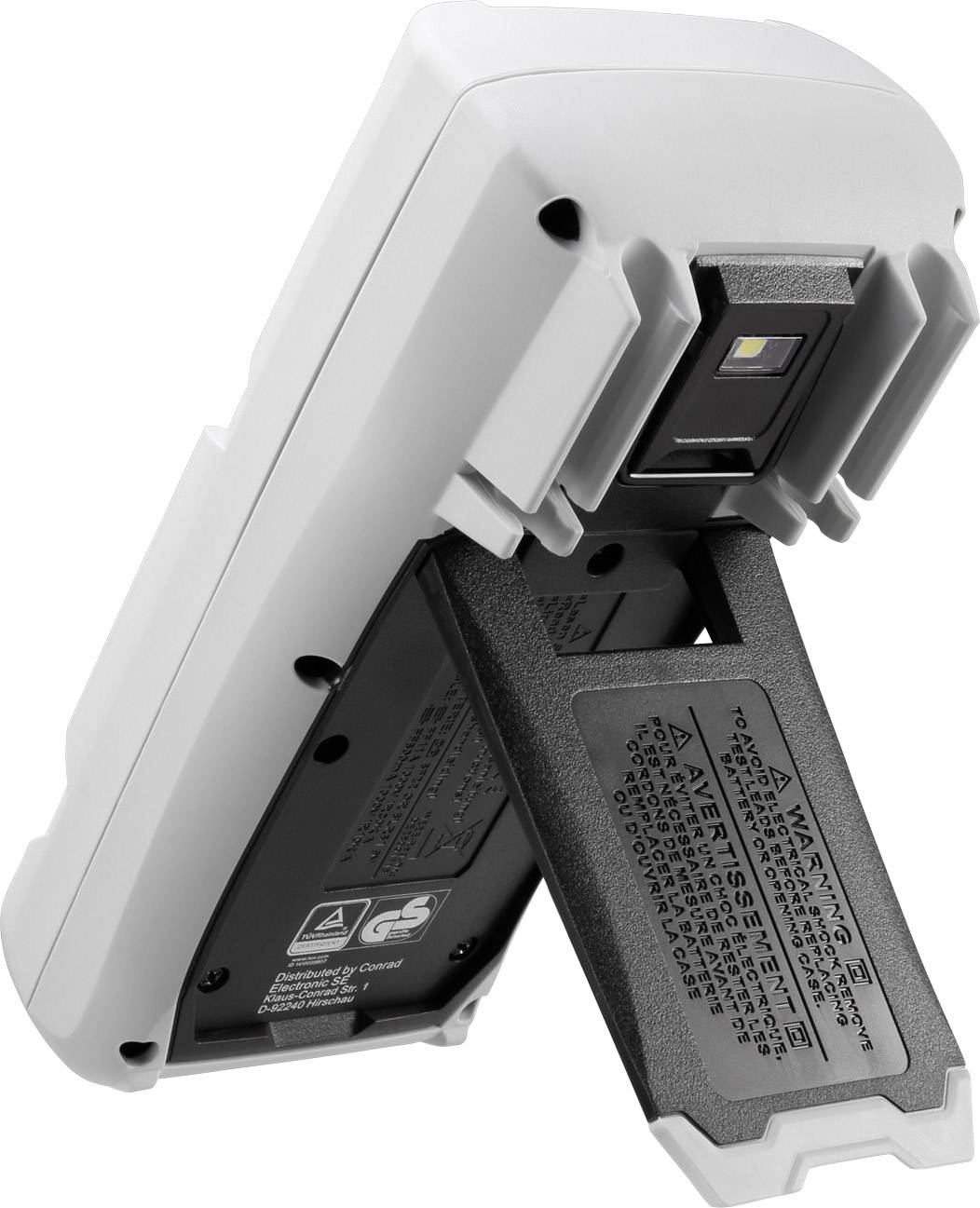 Egy elemmel működő készülék, kissé ferdén oldalról lefényképezve, mutatja a nyitott elemtartót és az alatta lévő figyelmeztető feliratokat.