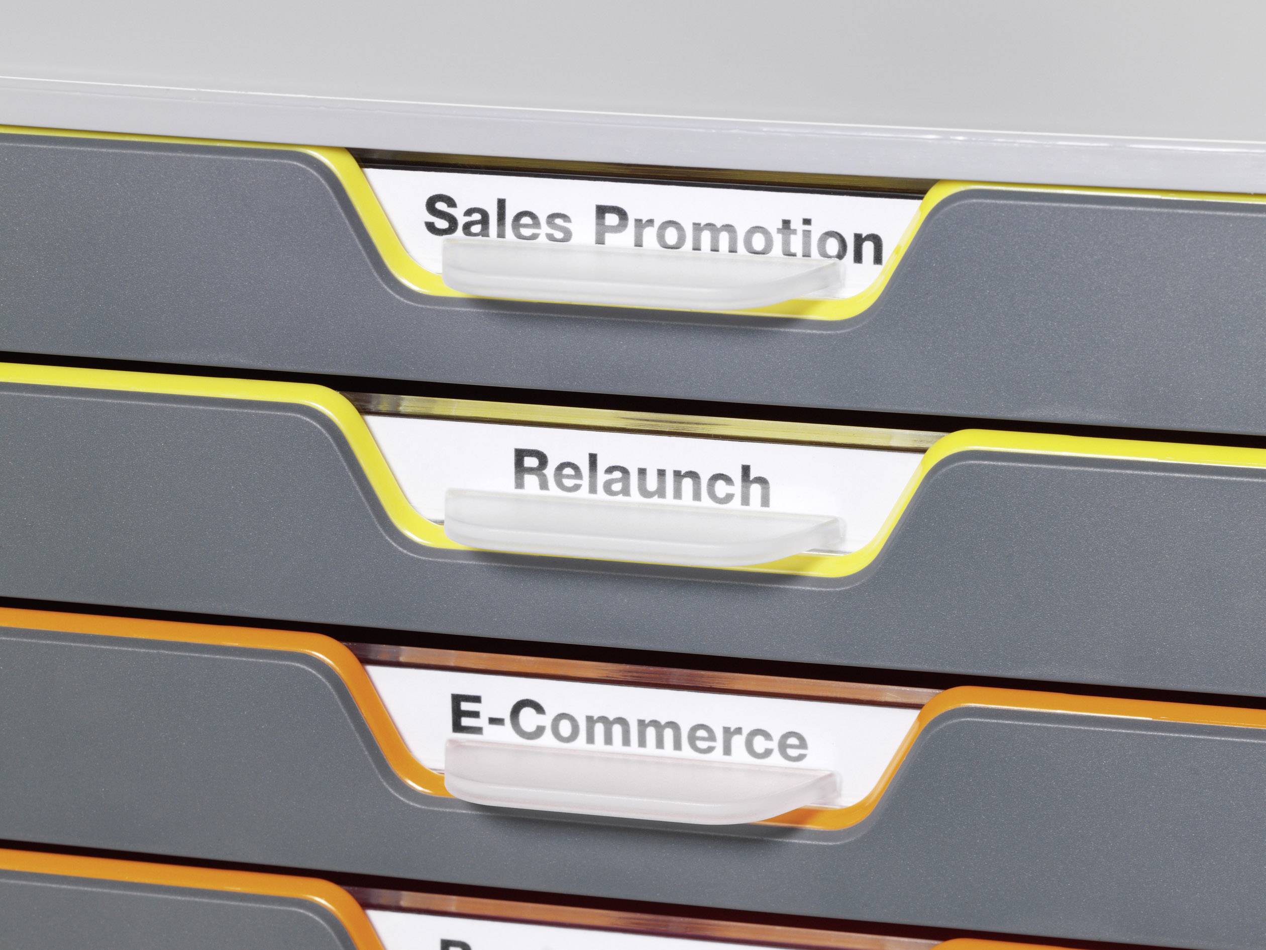 Tolófiókos irattartó egy irodában. A fiókokat a 'Sales Promotion', 'Relaunch' és 'E-Commerce' feliratok címkézik.