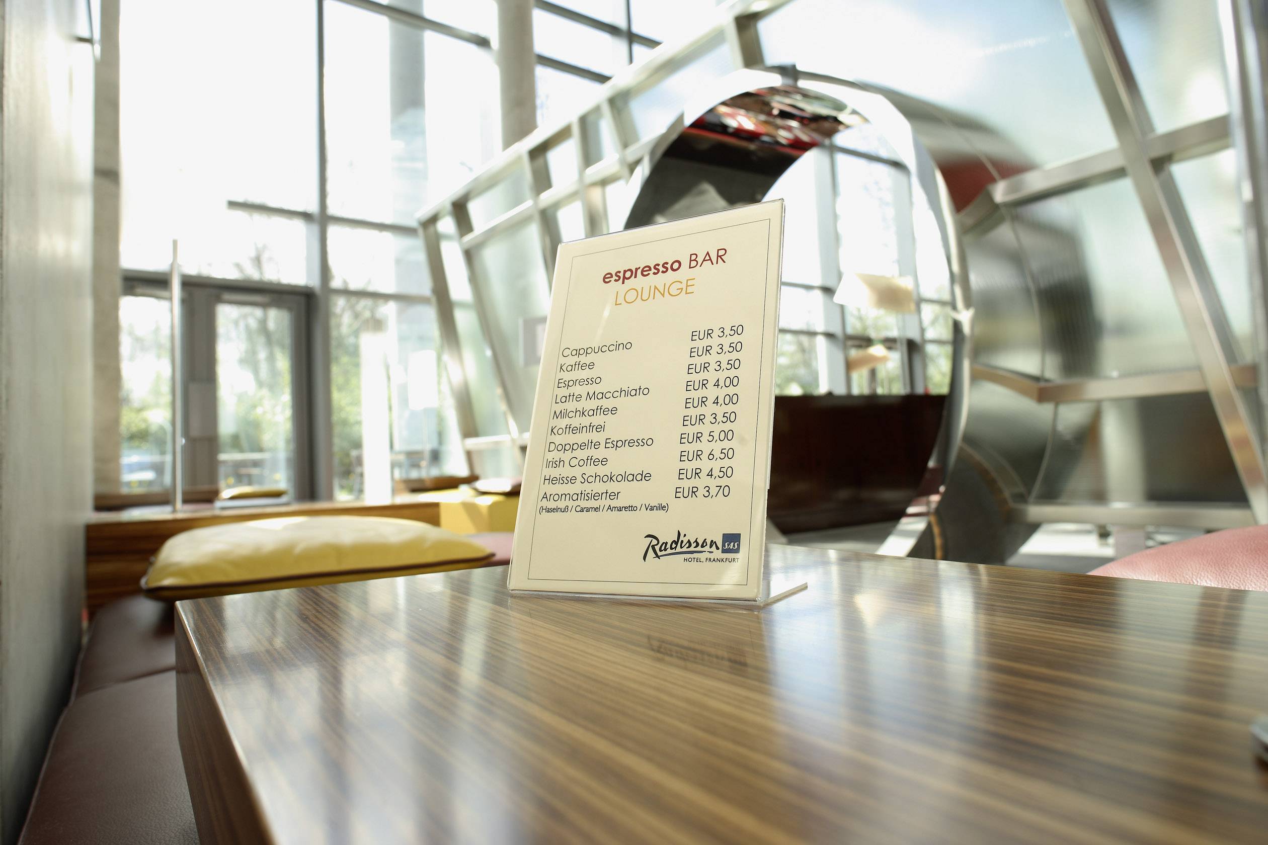 Étlap egy kávézóban, amely különböző kávéfajták árát mutatja, többek között a cappuccinóét és a latte macchiatóét, 3,50 EUR és 4,30 EUR között.