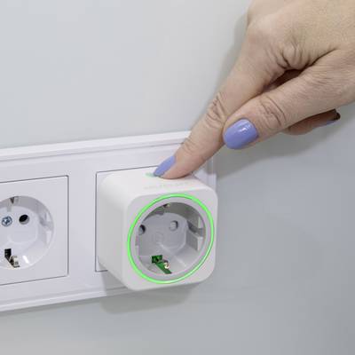 Egy kéz megnyomja egy fali digitális dugalj kapcsolóját, hogy be- vagy kikapcsoljon egy eszközt.
