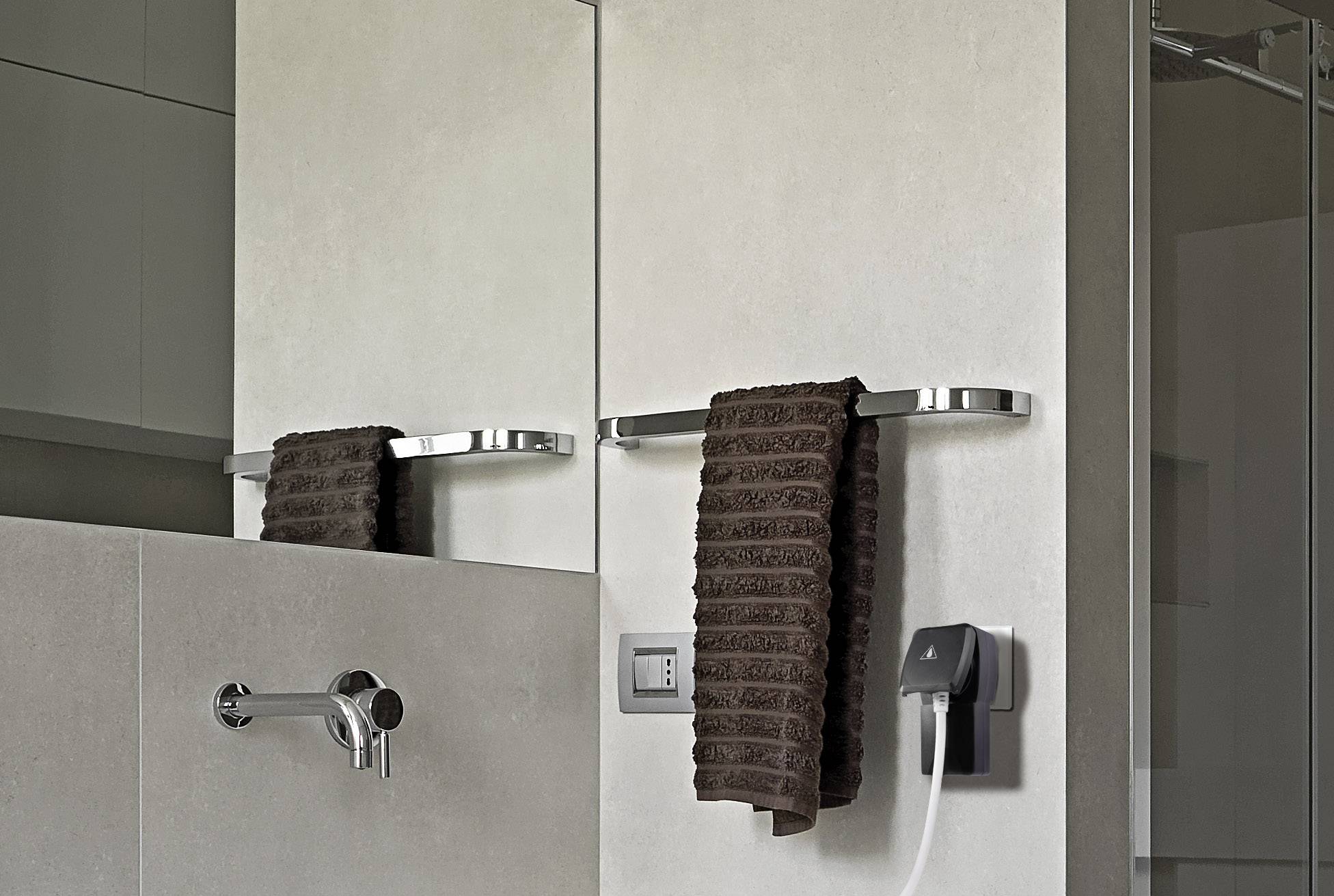 Egy modern fürdőszoba egy mosdókagylóval, egy barna törölközővel felszerelt törölközőtartóval és egy elektromos borotvával a fali dugaljban.