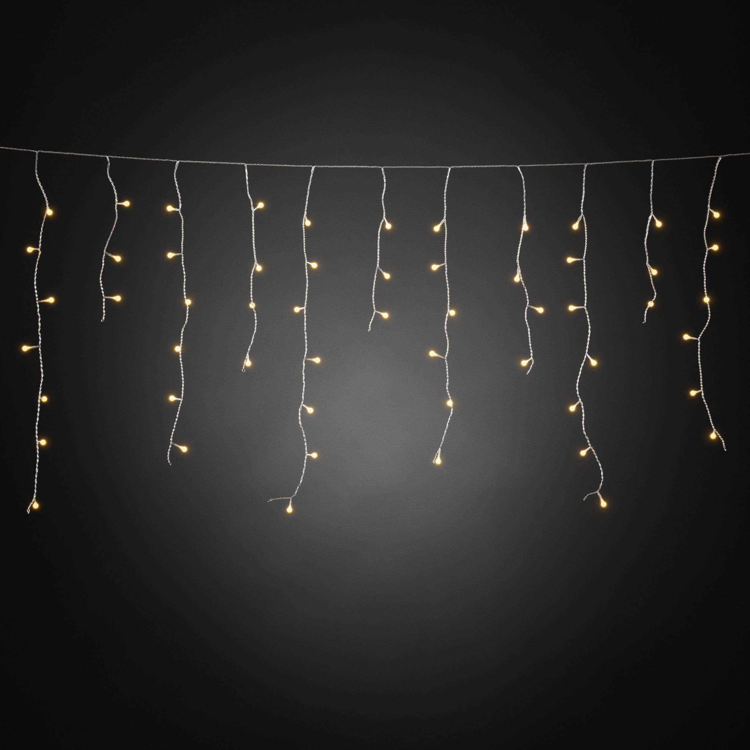 Meleg, sárga fényű fényfüzér lóg sötét háttér előtt. A lámpák egyenletesen vannak elosztva, és hangulatos atmoszférát teremtenek.