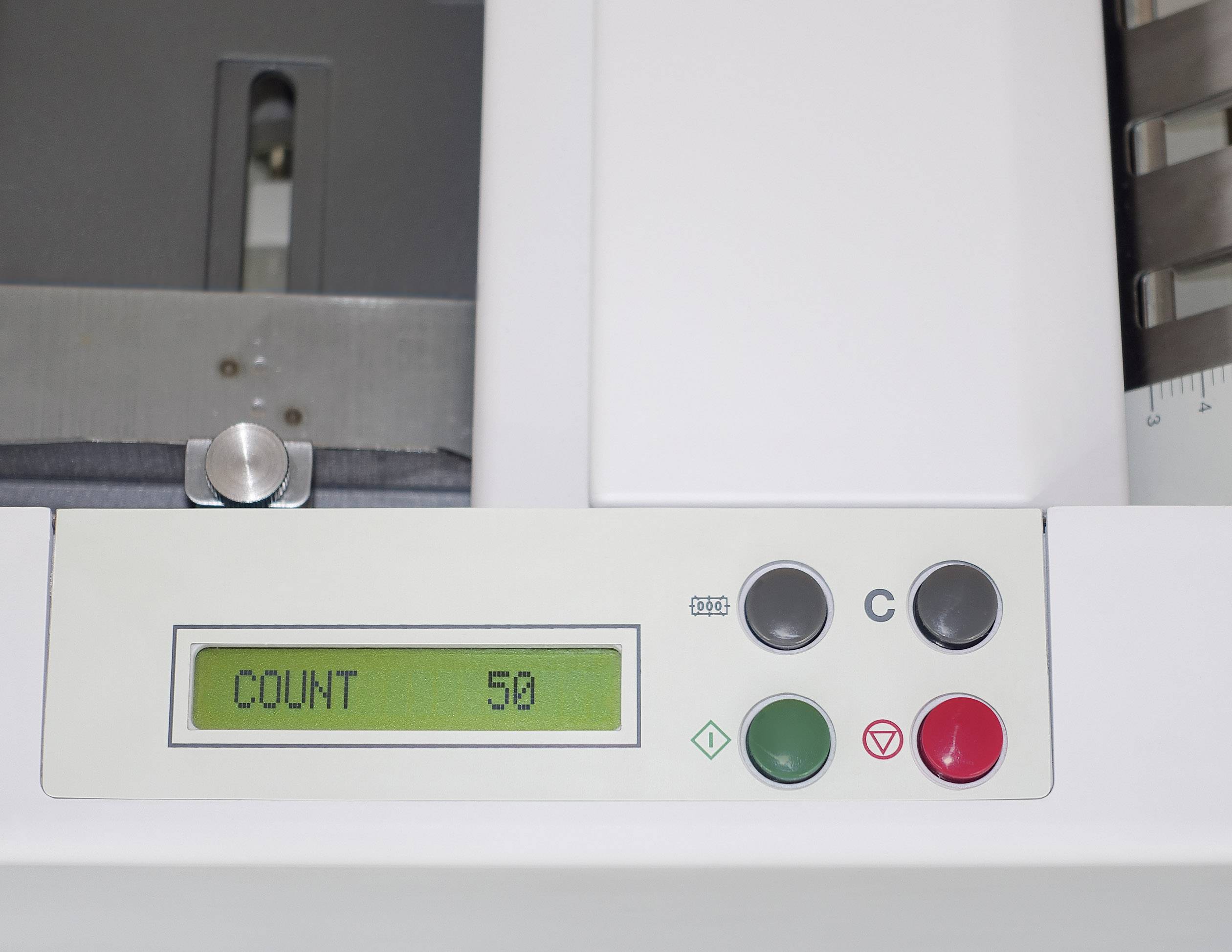 Egy számláló '50 DARAB' feliratot mutat egy digitális kijelzőn. Mellette négy, különböző színű gomb található a kezeléshez.