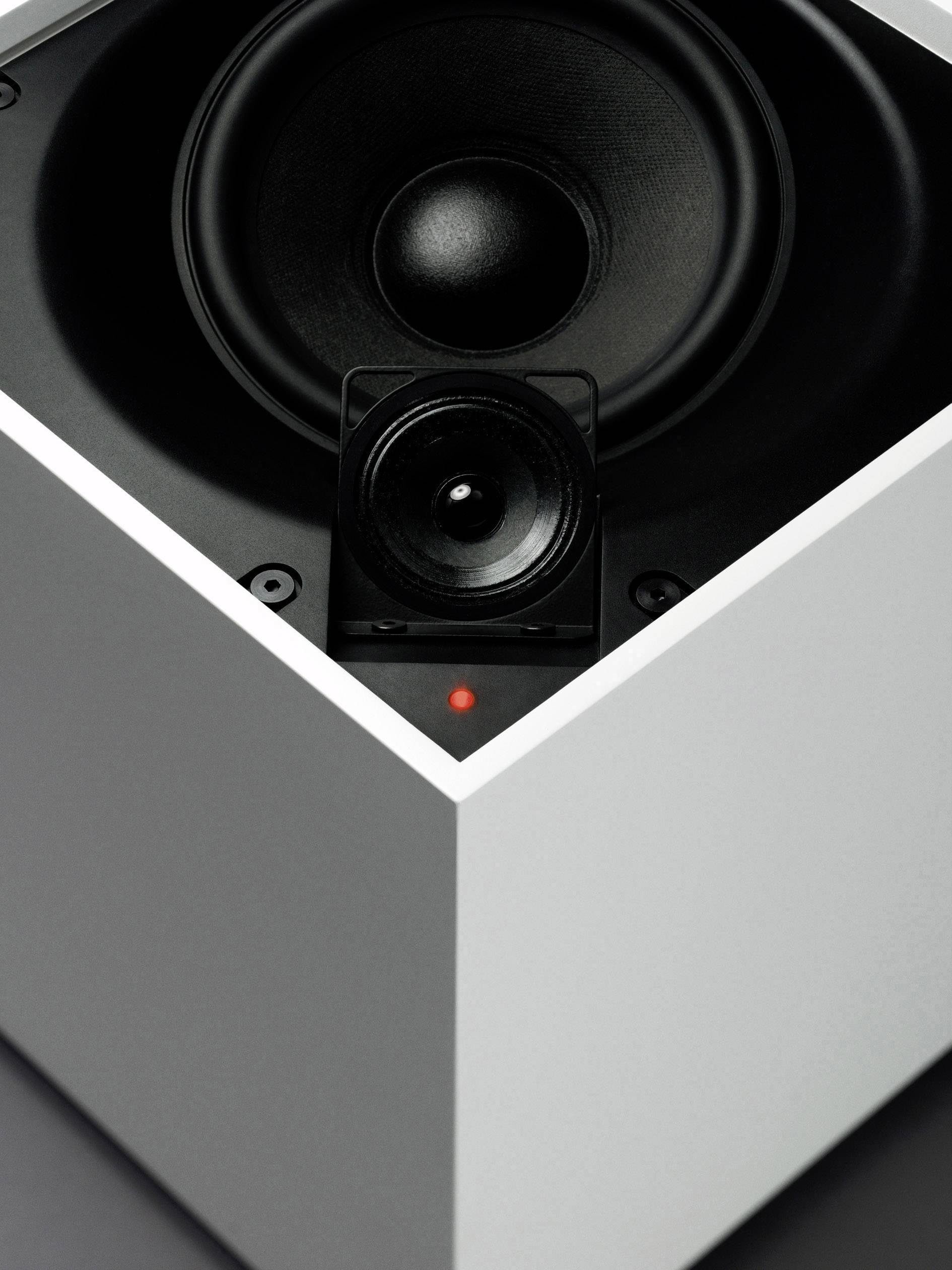 Egy hangszóró két különböző membránnal fehér házban. Egy piros jelzőfény látható az elején.