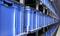 Kék műanyag tárolódobozok egy magas polcon egy raktárban; a dobozok egyenletesen vannak egymásra pakolva és használatra készen állnak.