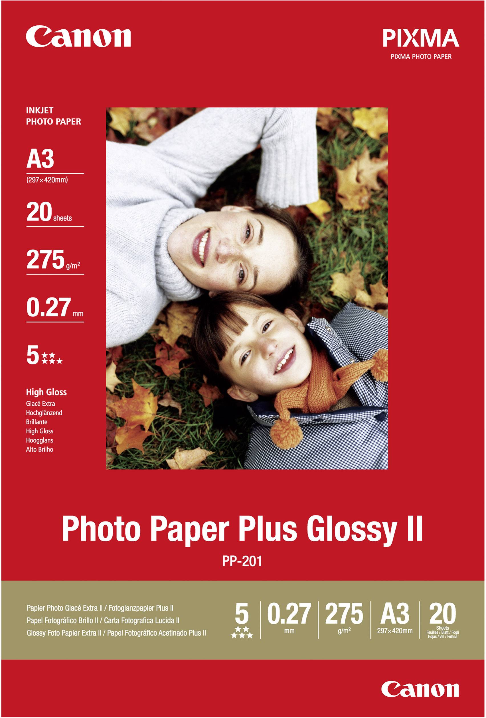 Egy gyermek és egy nő mosolyogva fekszenek őszi leveleken. A 'Canon Photo Paper Plus Glossy II' termék csomagolása termékinformációkkal.