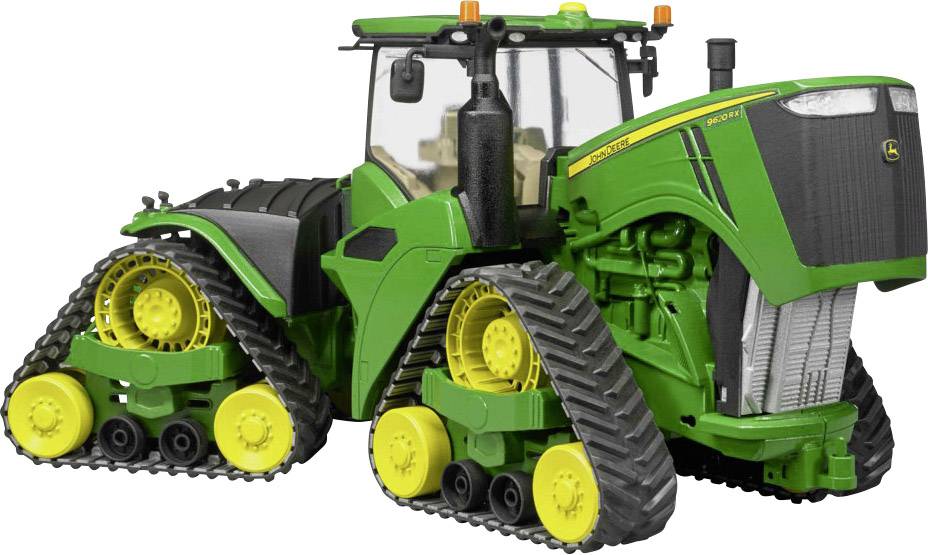 Zöld traktor négy lánctalppal áll szürke talajon. A traktor nagy méretű, és zárt, üvegezett fülkével rendelkezik.