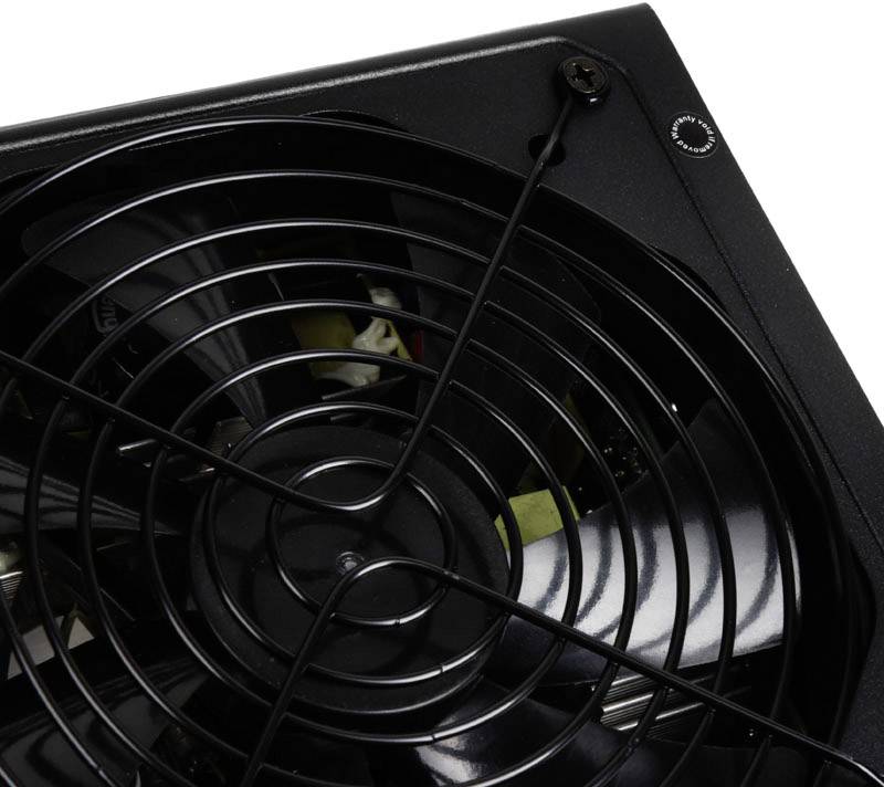 Egy fekete számítógép-ventilátor védőráccsal, amely egy házba van beépítve, részletes ventilátorlapátokat és csavarokat mutat.