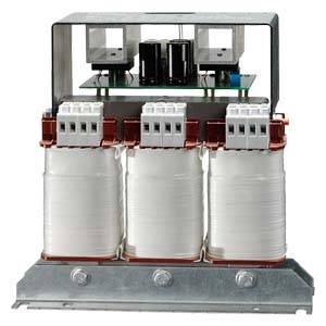 Egy háromfázisú transzformátor három fehérre tekert tekerccsel és elektronikai alkatrészekkel egy fémlemezen.