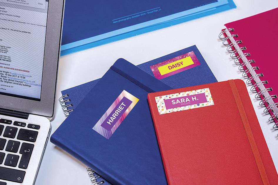 'Három füzet Harriet, Daisy és Sara H. nevével egy laptop mellett fekszik. Egy kék füzet látható a háttérben.'