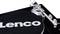 Közeli felvétel egy lemezjátszóról, amelynek fedőlapján a 'Lenco' felirat olvasható. A hangkar a jobb oldalon látható.