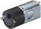 Egy fém DC-motor fekete és szürke házban. Elöl kerek hajtótengellyel rendelkezik és kompakt kialakítású.
