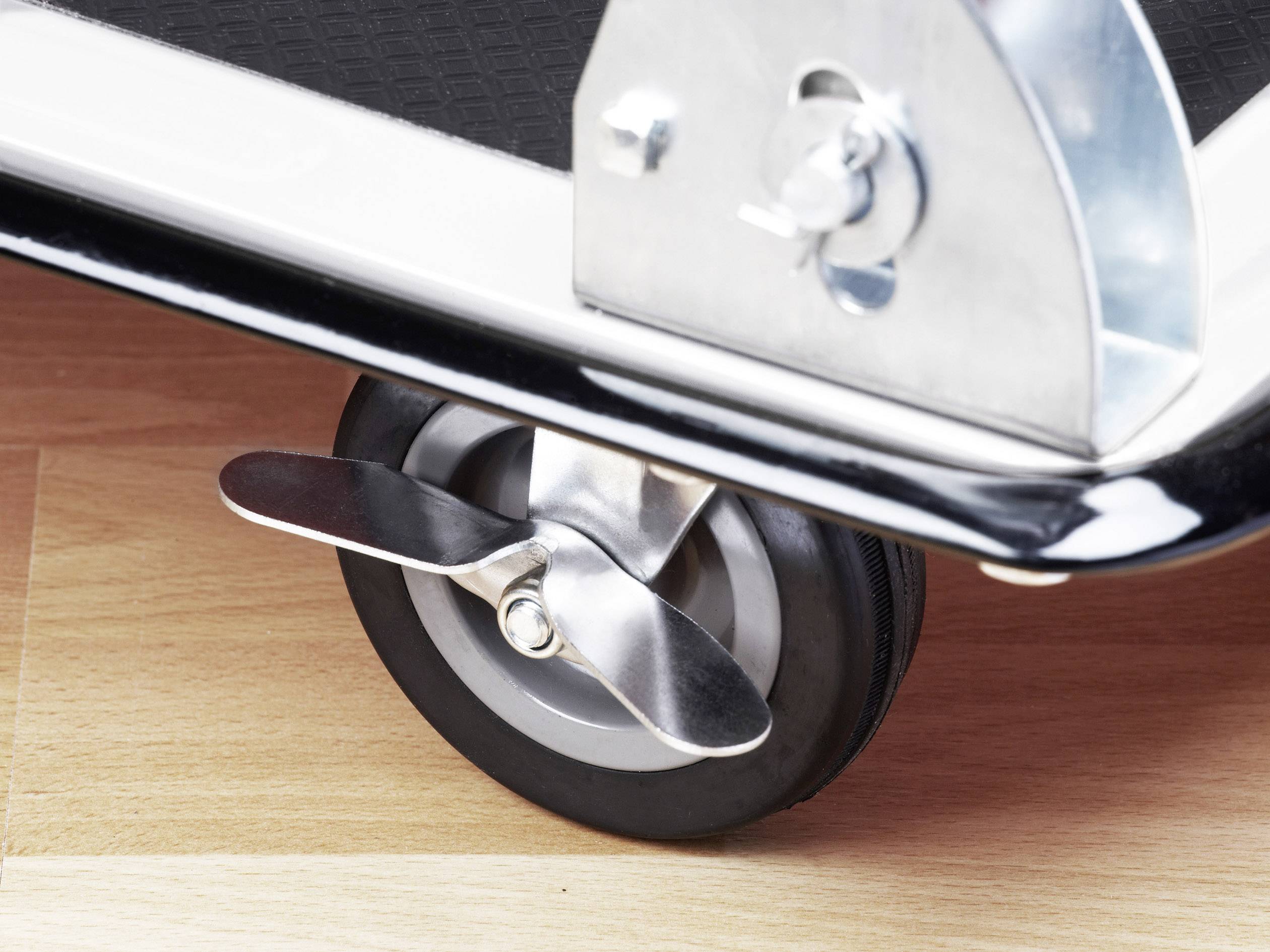 Egy fémkerék közeli felvétele fékkel fa padlón. A kerék egy szállítókocsi része.