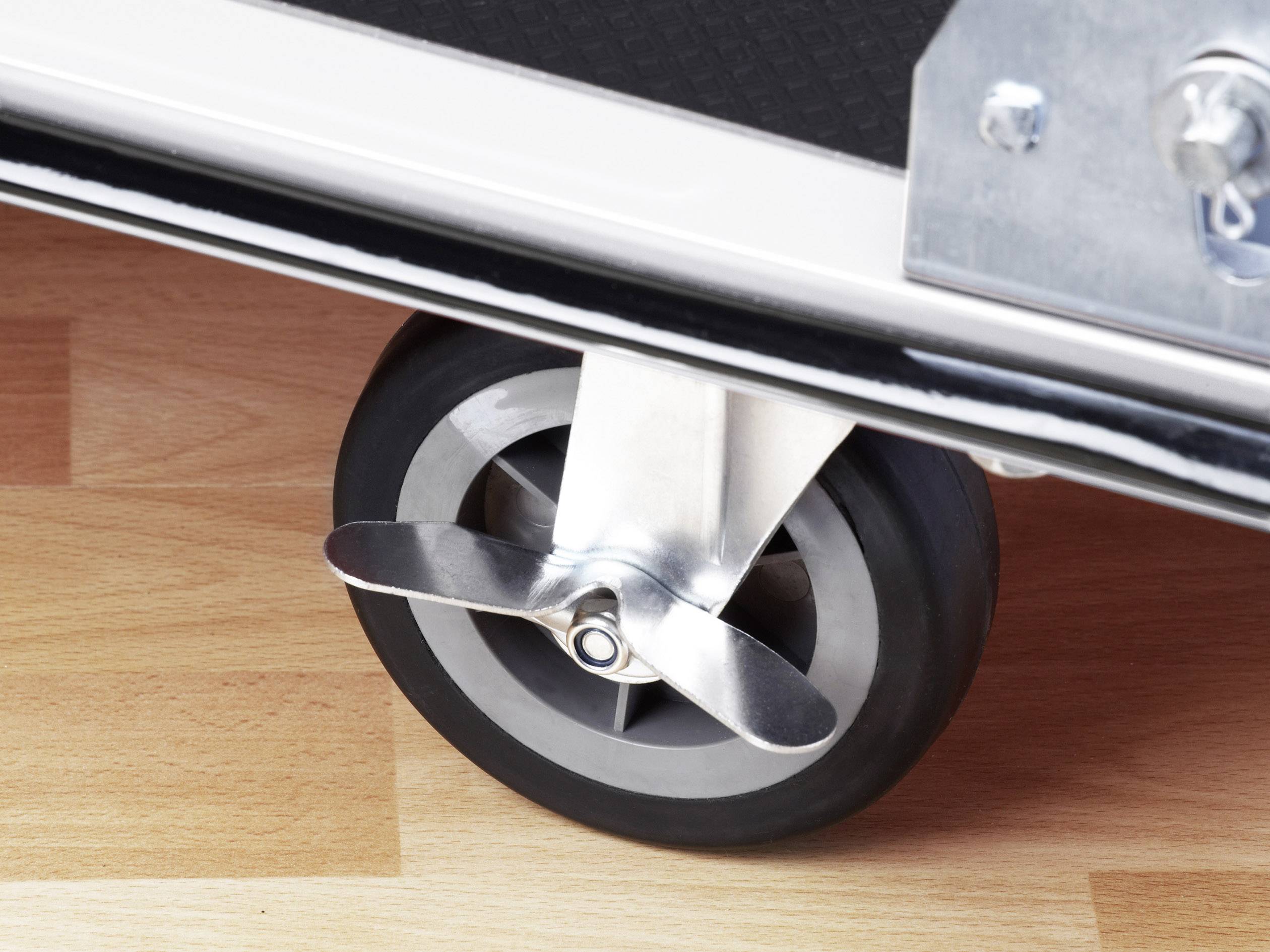 Egy repülőgép-mintás gurulós bőrönd közelképe, propeller formájú kerékdísszel fapadlón.