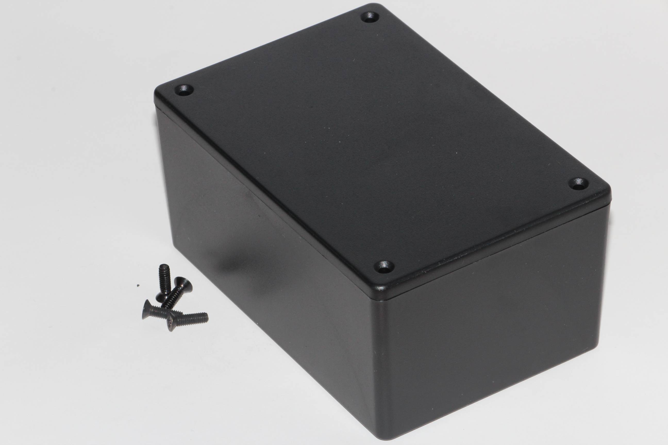 Fekete négyszögletes ház négy csavarral; alkalmas elektronikai projektek vagy házilagos szerelési egységek számára.