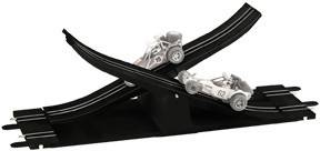 Két játékautó egy fekete, kereszteződő autópályán. Az egyik autó felrepül, míg a másik egy alsóbb sávban marad.