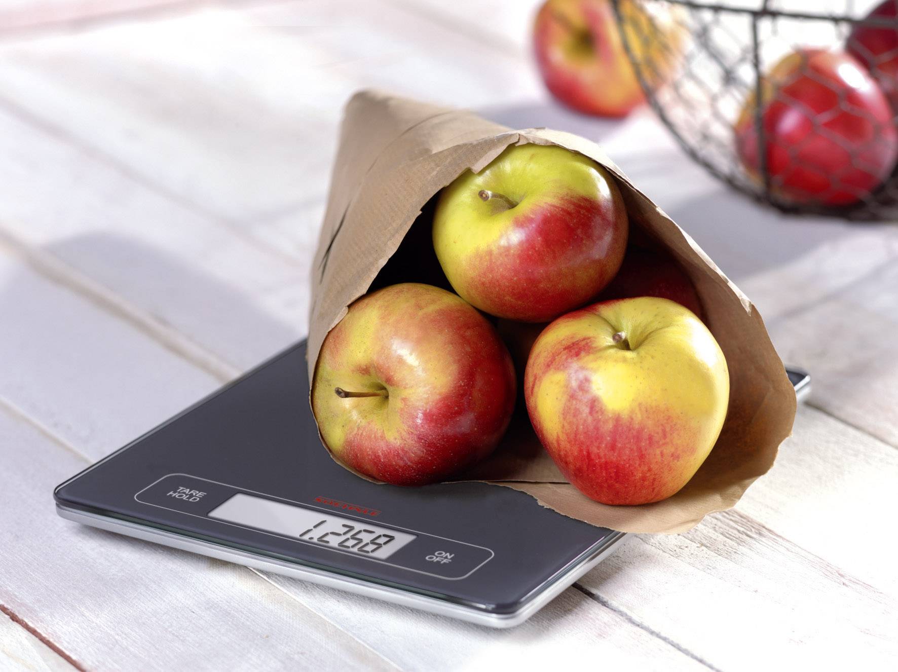Három alma egy papírzacskóban egy konyhai mérleg tetején, amelynek súlya 1,268 kg