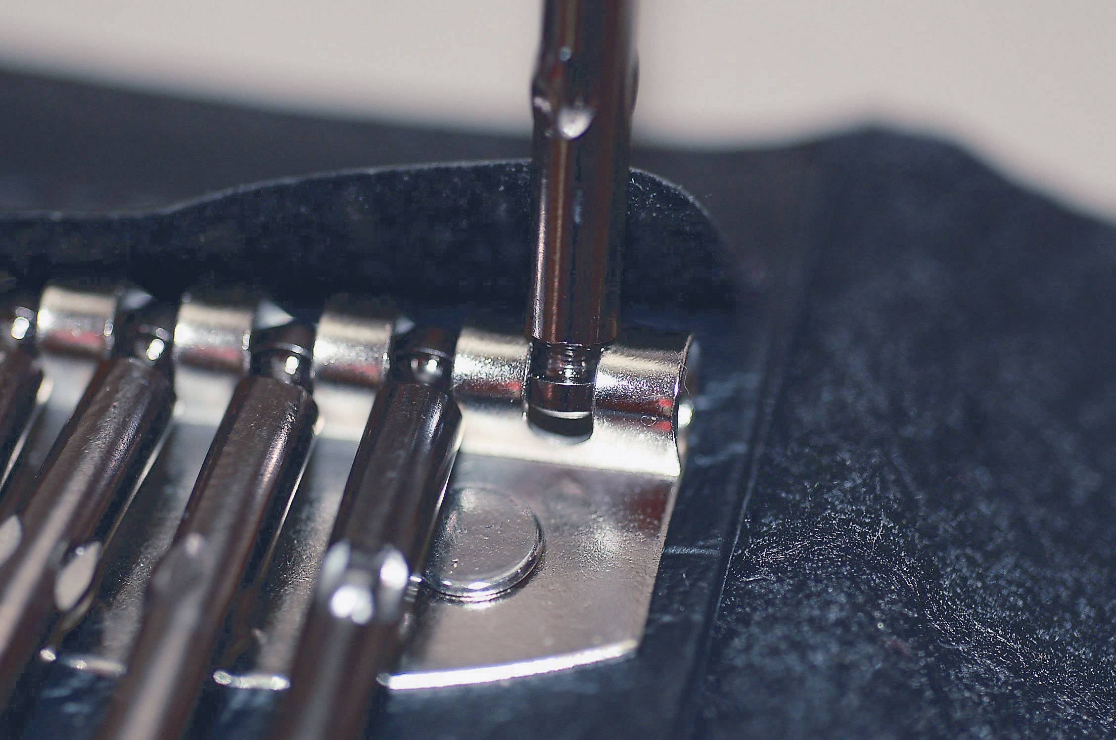 Egy csavarhúzó egy csavart rögzít egy fémszerkezeten. A kép a szerelési folyamat közeli felvételét mutatja.