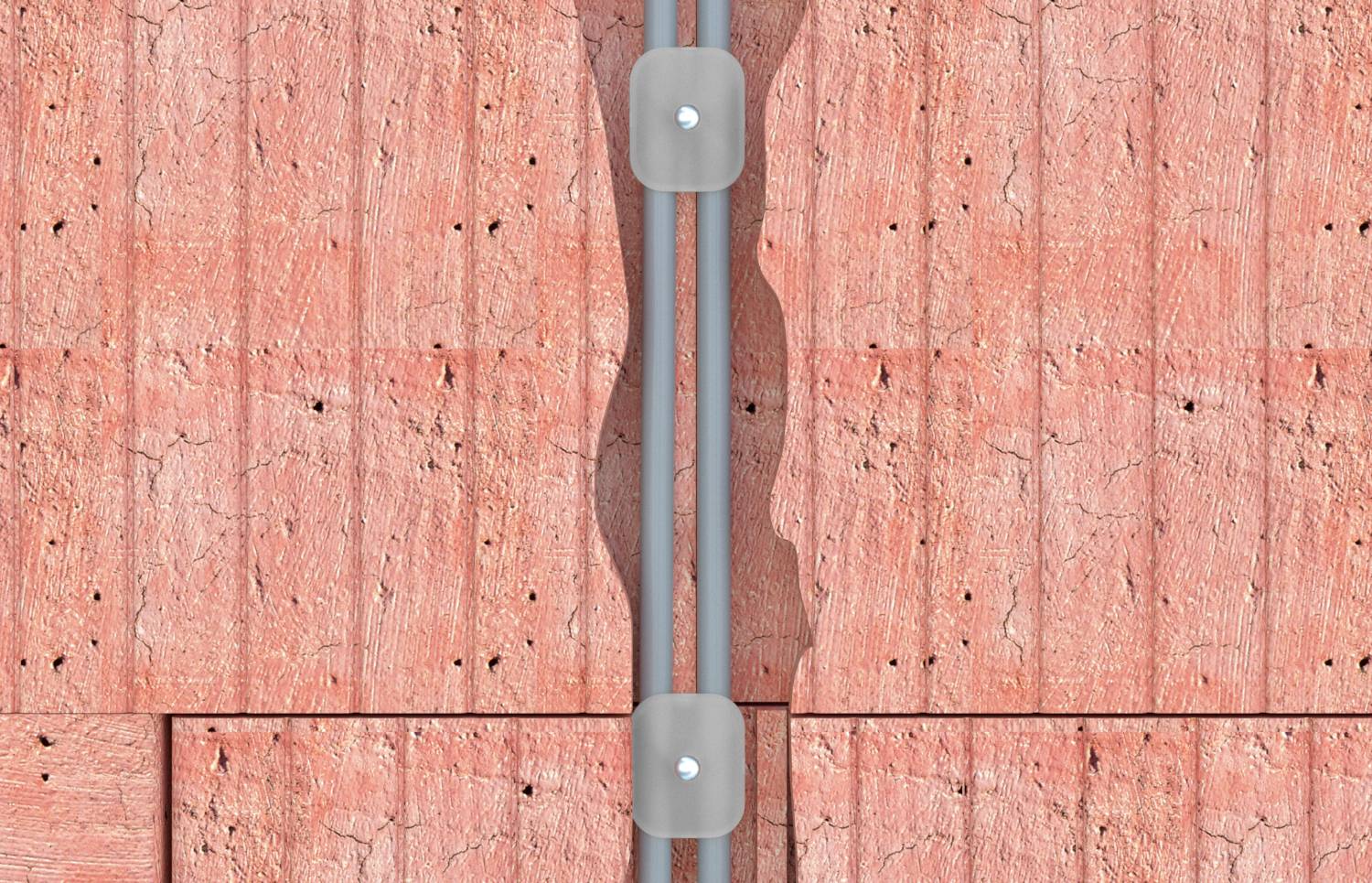 Due condotti elettrici grigi corrono verticalmente attraverso una parete in legno, fissati da piccole staffette metalliche.