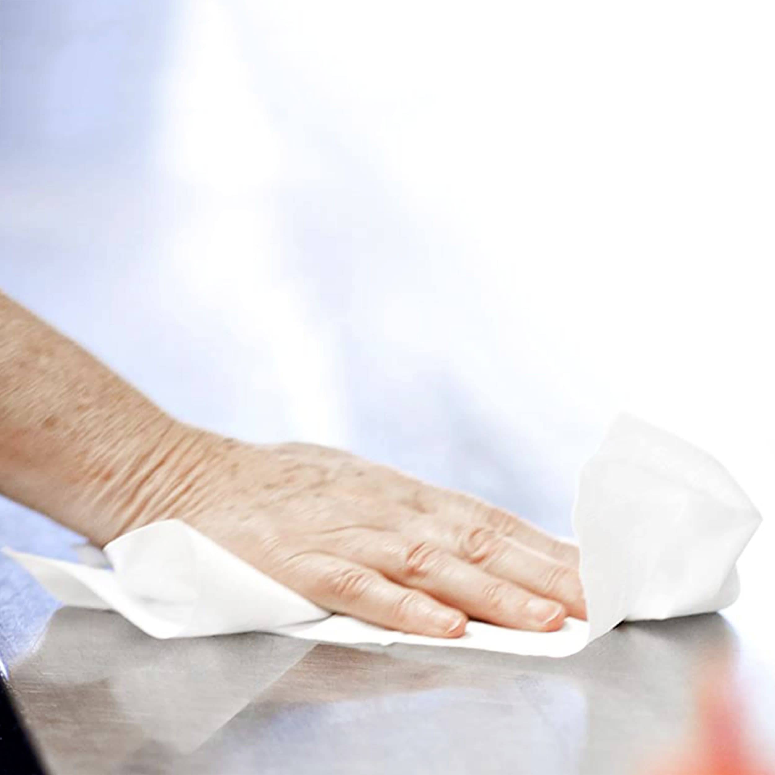 Una mano passa un panno bianco su una superficie liscia, presumibilmente per pulirla.