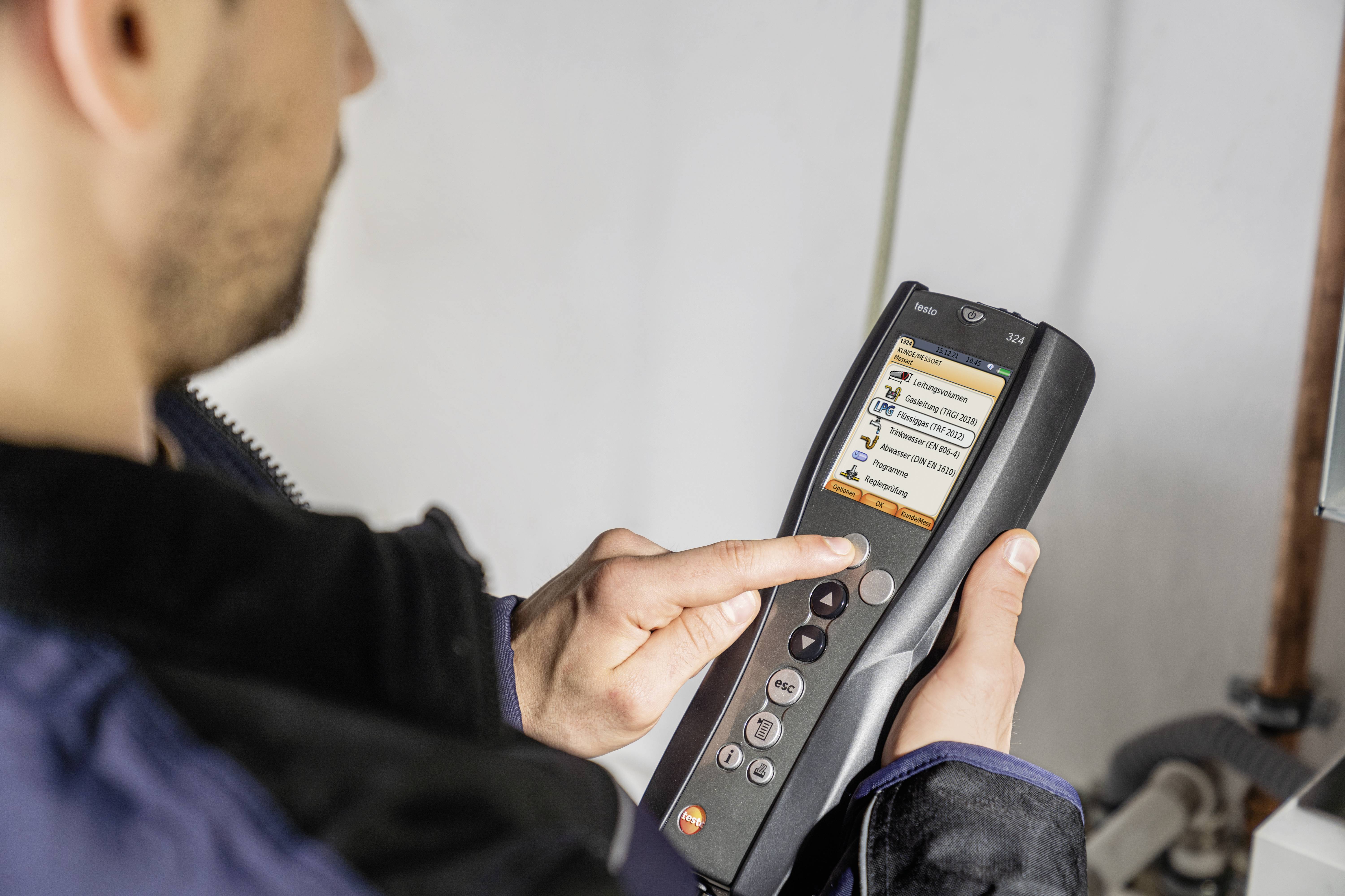 Una persona sta utilizzando uno strumento di misurazione portatile con display digitale che mostra importanti informazioni di sistema. Sullo sfondo, l'immagine è sfocata.