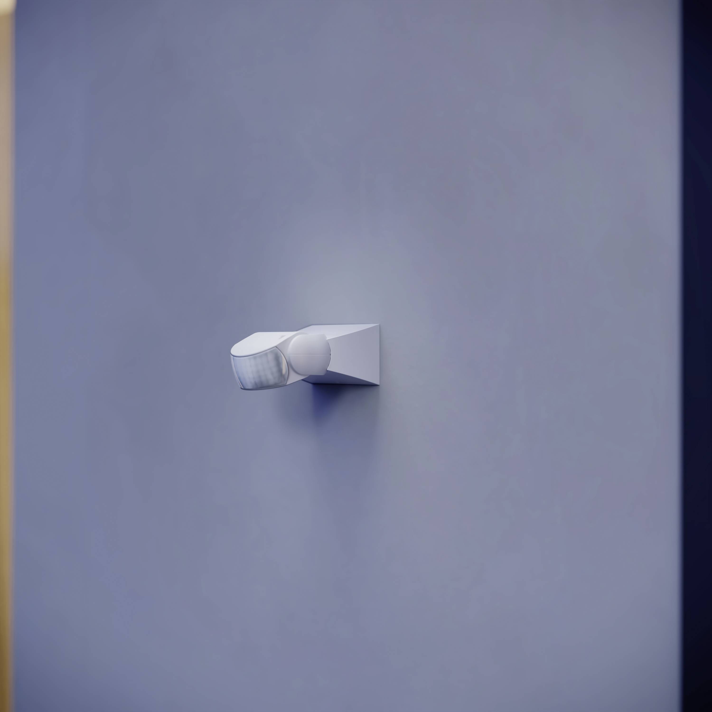 Un singolo faretto bianco illumina una parete liscia grigia.