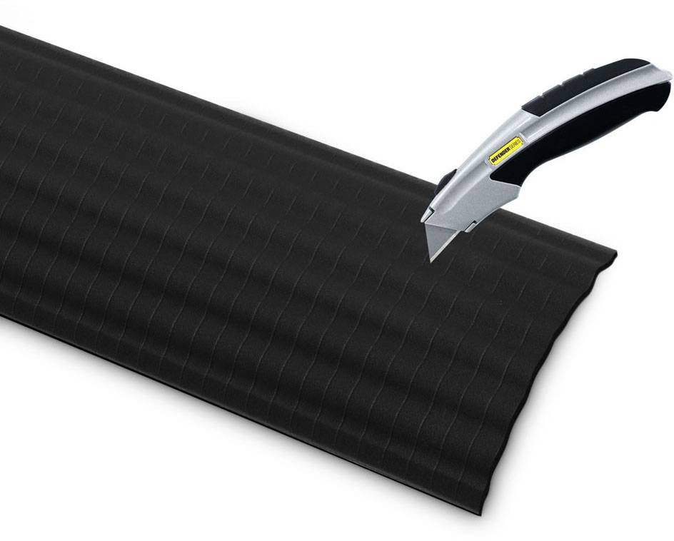 Materiale ondulato nero in plastica, tagliato con un taglierino argentato.