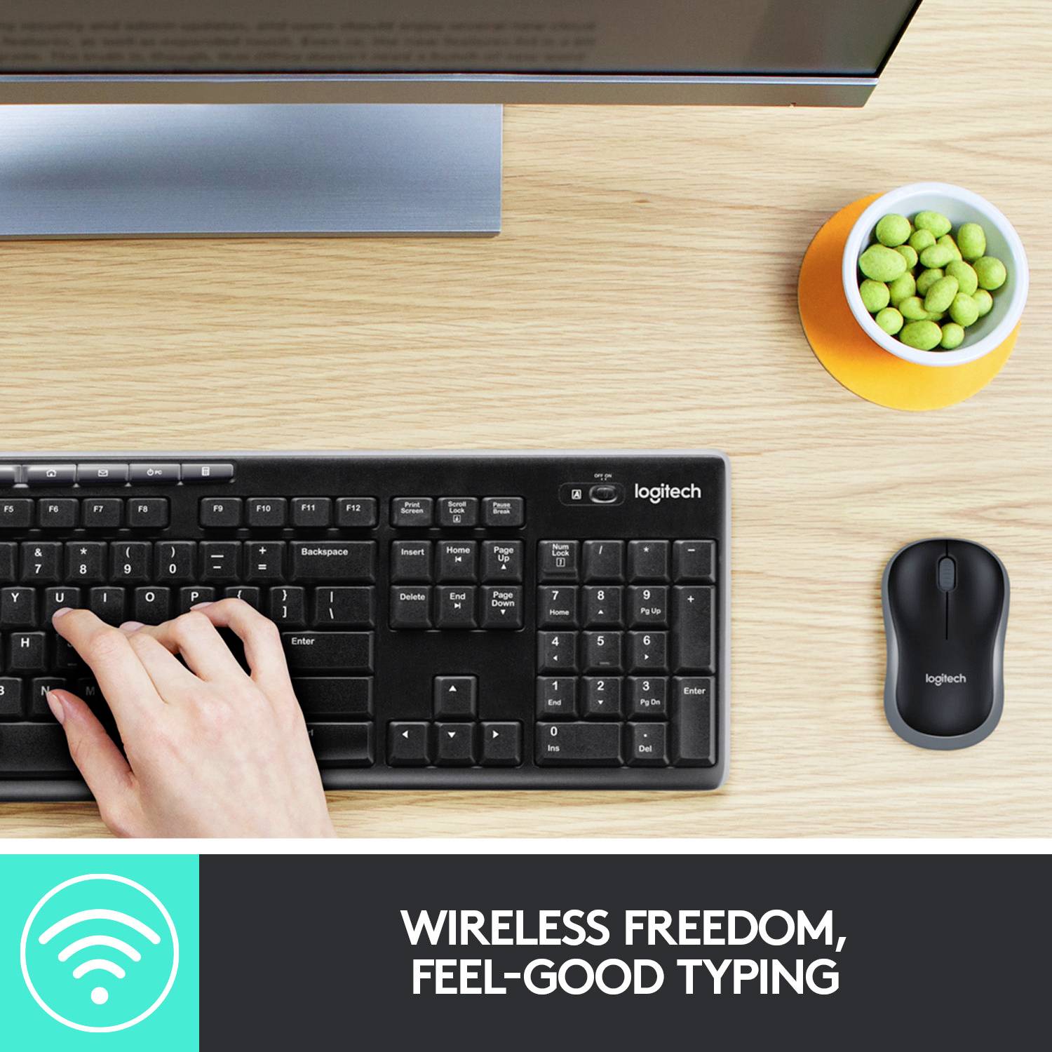 'Libertà senza fili, digitazione confortevole'. Mano che digita su una tastiera wireless accanto al mouse e a una ciotola di snack sulla scrivania.