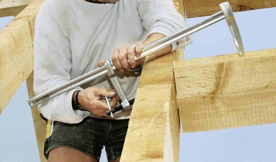 Un artigiano usa una grande chiave inglese per assemblare due travi di legno.