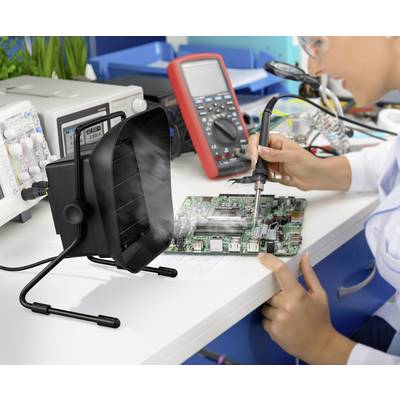 Una persona sta saldando su una scheda elettronica in un ambiente di laboratorio, con un dispositivo di estrazione dei fumi e strumenti di misurazione sullo sfondo.