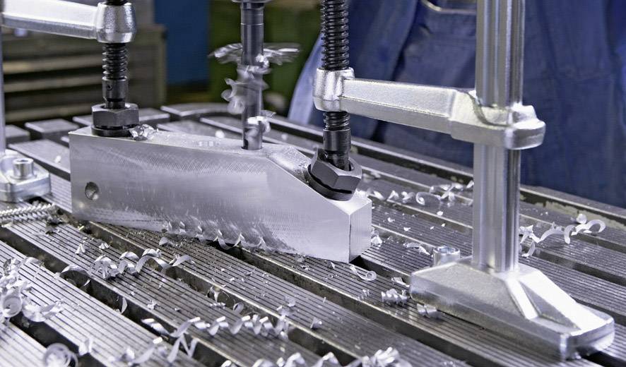 Una lamiera metallica viene lavorata da una macchina con mandrini per foratura. Trucioli di metallo sono sparsi sul tavolo. Produzione industriale.