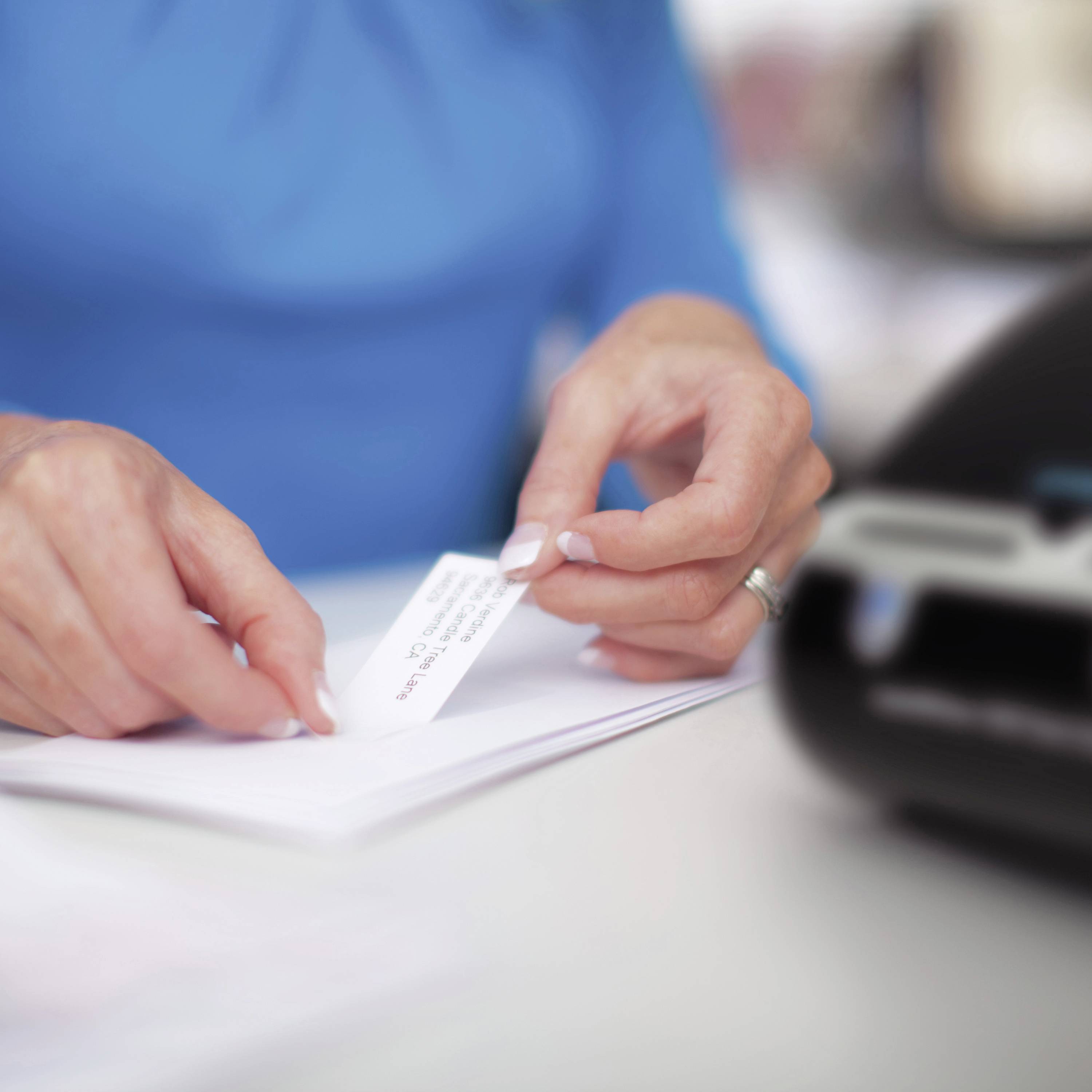 Una persona inserisce una lettera in una stampante. La lettera contiene testo stampato.