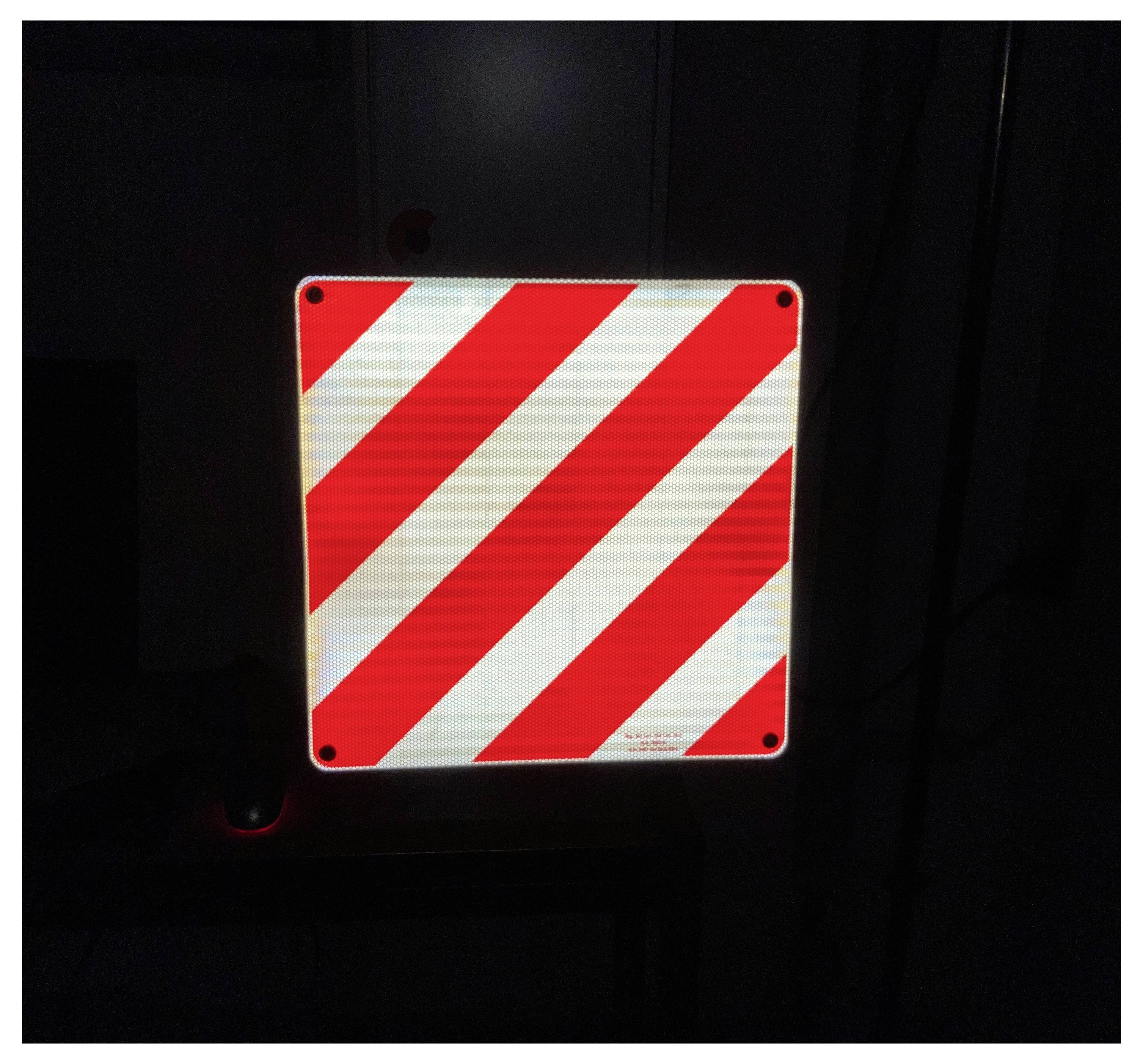 Cartello di avvertimento riflettente rosso e bianco con strisce diagonali, comunemente utilizzato per segnalare aree pericolose.