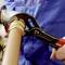 Una persona in una tuta blu sta riparando un tubo di rame con una pinza regolabile.