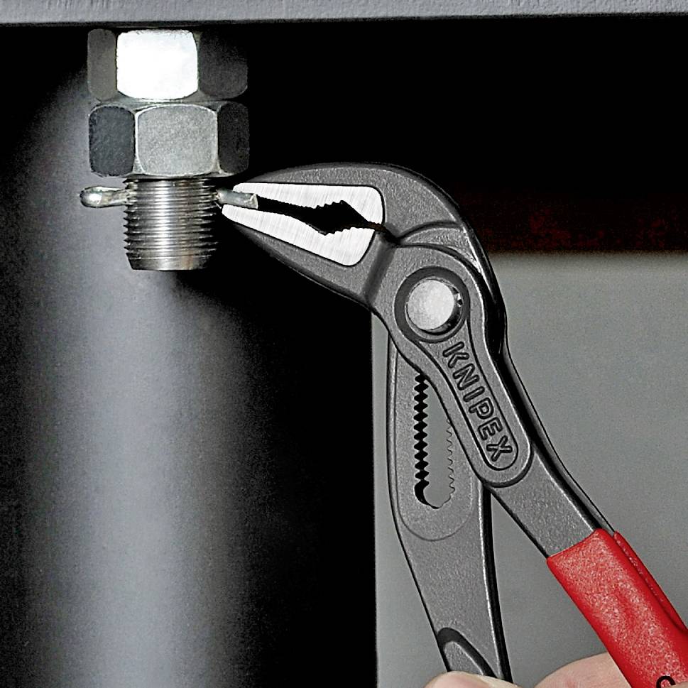 Una mano tiene una pinza idraulica agganciata a un dado metallico. La pinza è stretta saldamente e mostra un'attività artigianale.