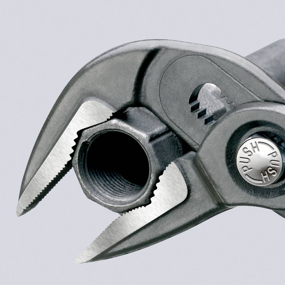 Primo piano di una chiave inglese regolabile che tiene un componente metallico rotondo con superficie zigrinata. Testo 'PUSH' sulla vite.