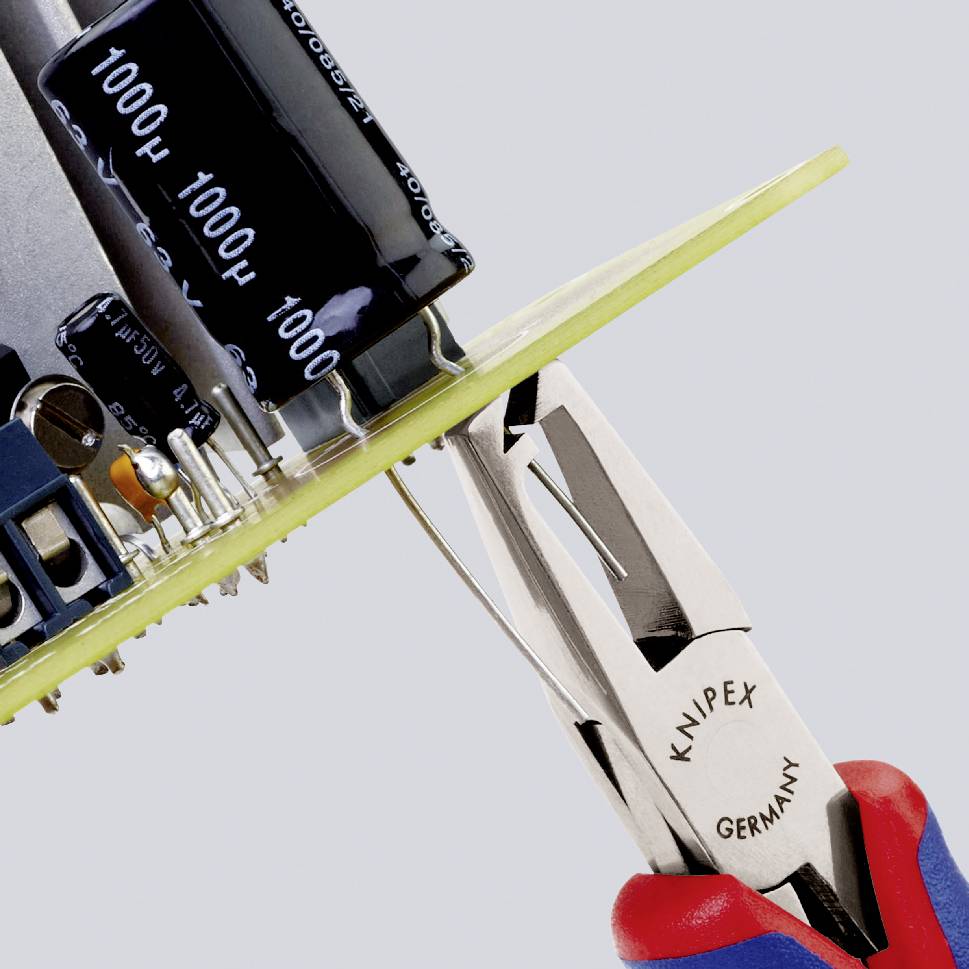 Una scheda elettronica viene lavorata con un utensile Knipex. Un condensatore e altri componenti elettronici sono visibili.