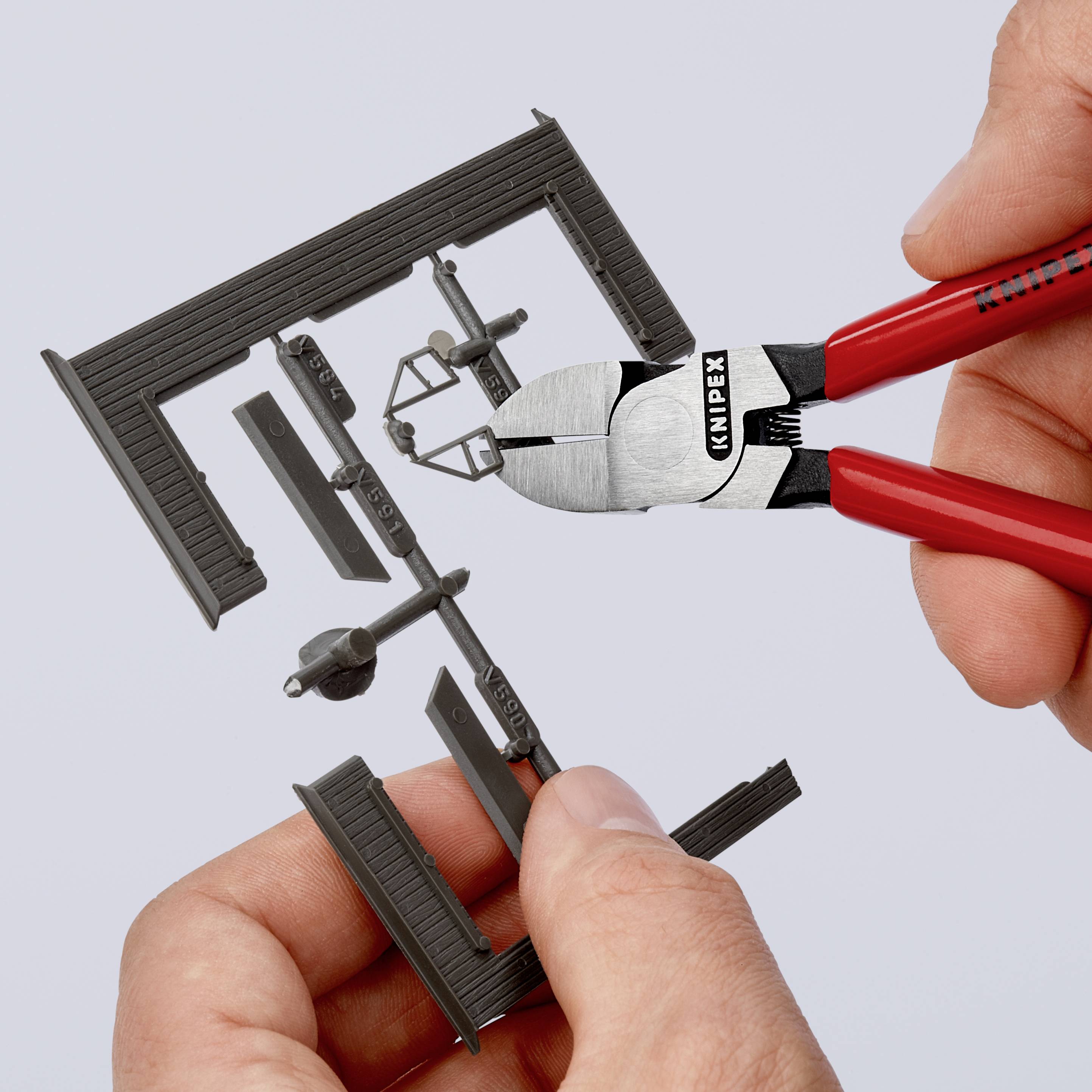 Due mani tengono una pinza Knipex che taglia un telaio nero per modellismo.