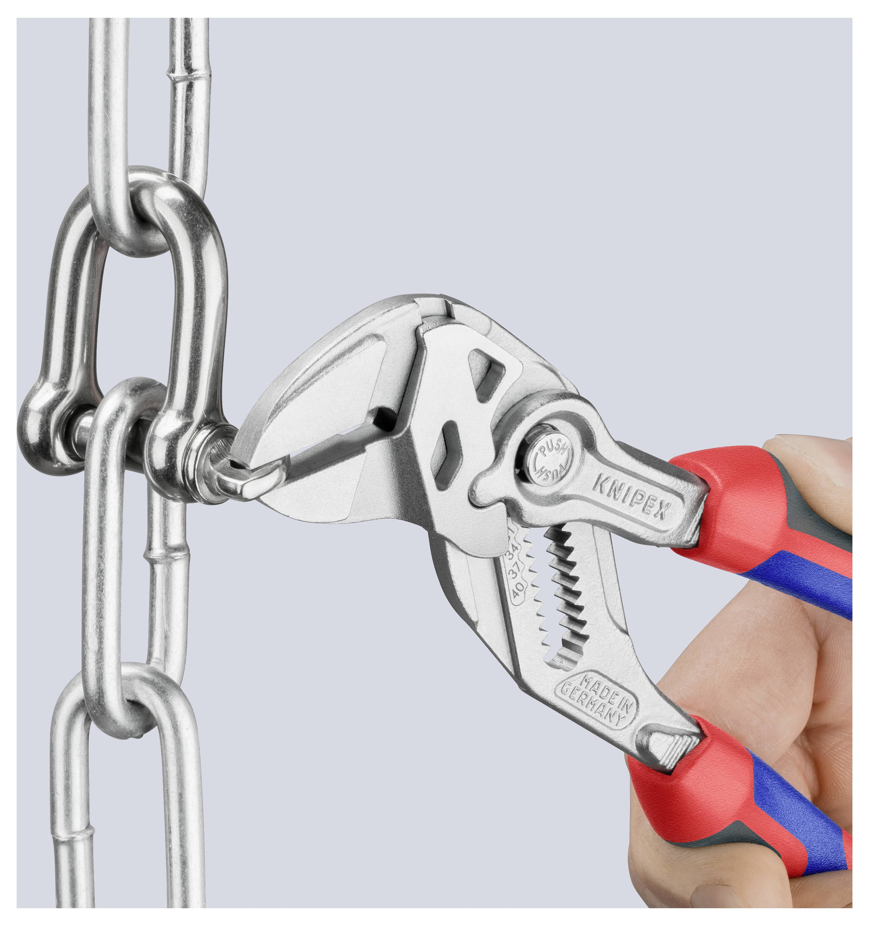 Una mano utilizza pinze regolabili per tagliare un anello di catena metallica, dimostrando la funzione di taglio dello strumento.