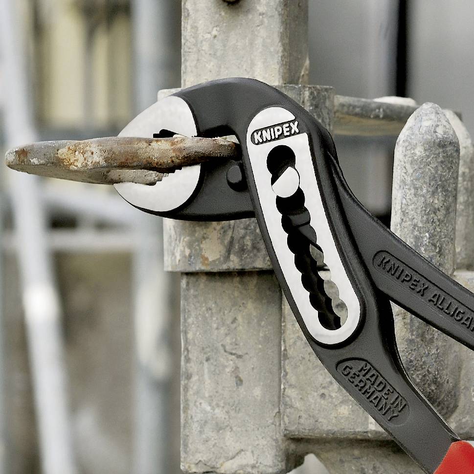 Una pinza del marchio Knipex tiene un chiodo arrugginito in una griglia metallica.