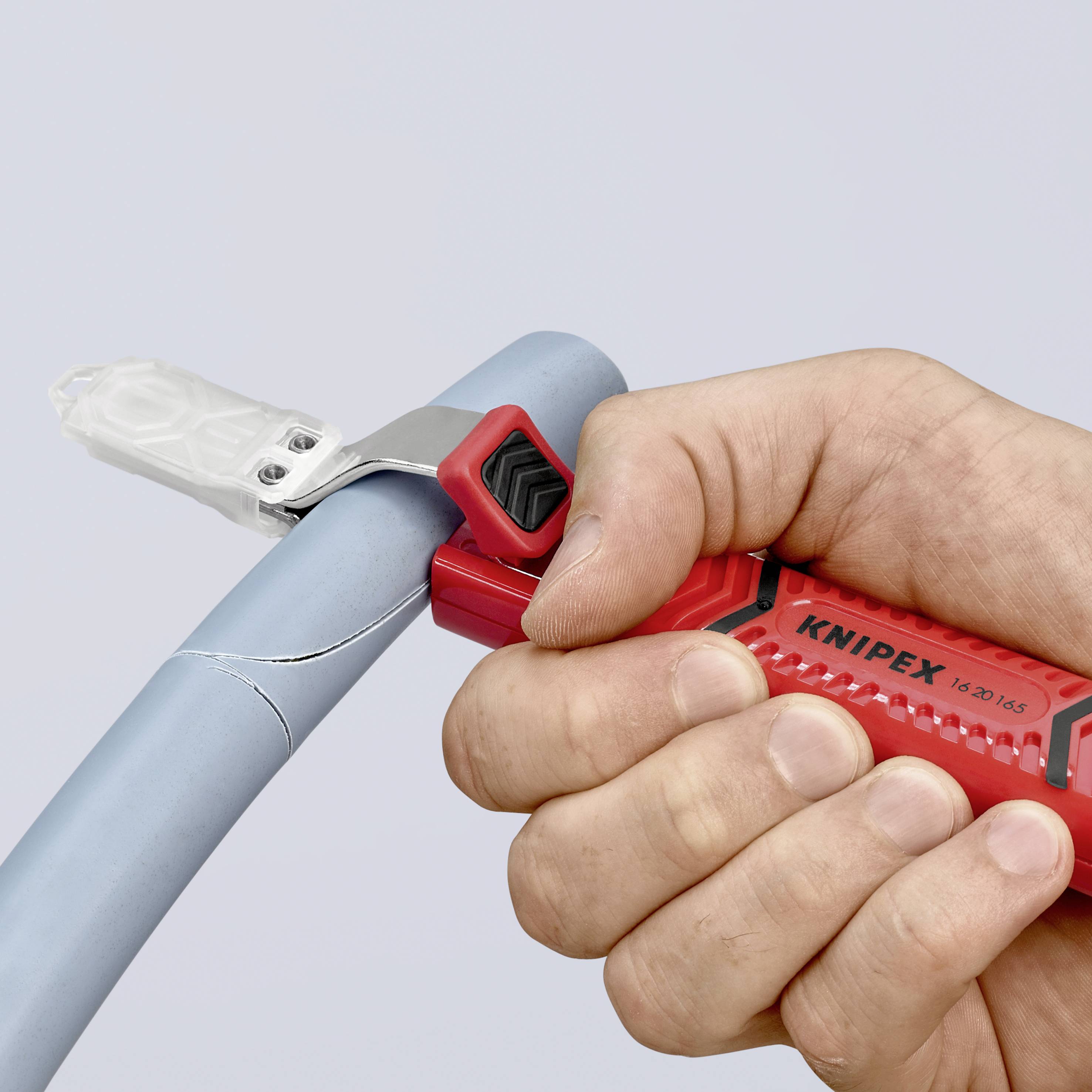 Una persona sta tagliando un tubo azzurro chiaro con un utensile rosso KNIPEX. L'immagine mostra un primo piano del processo di taglio.