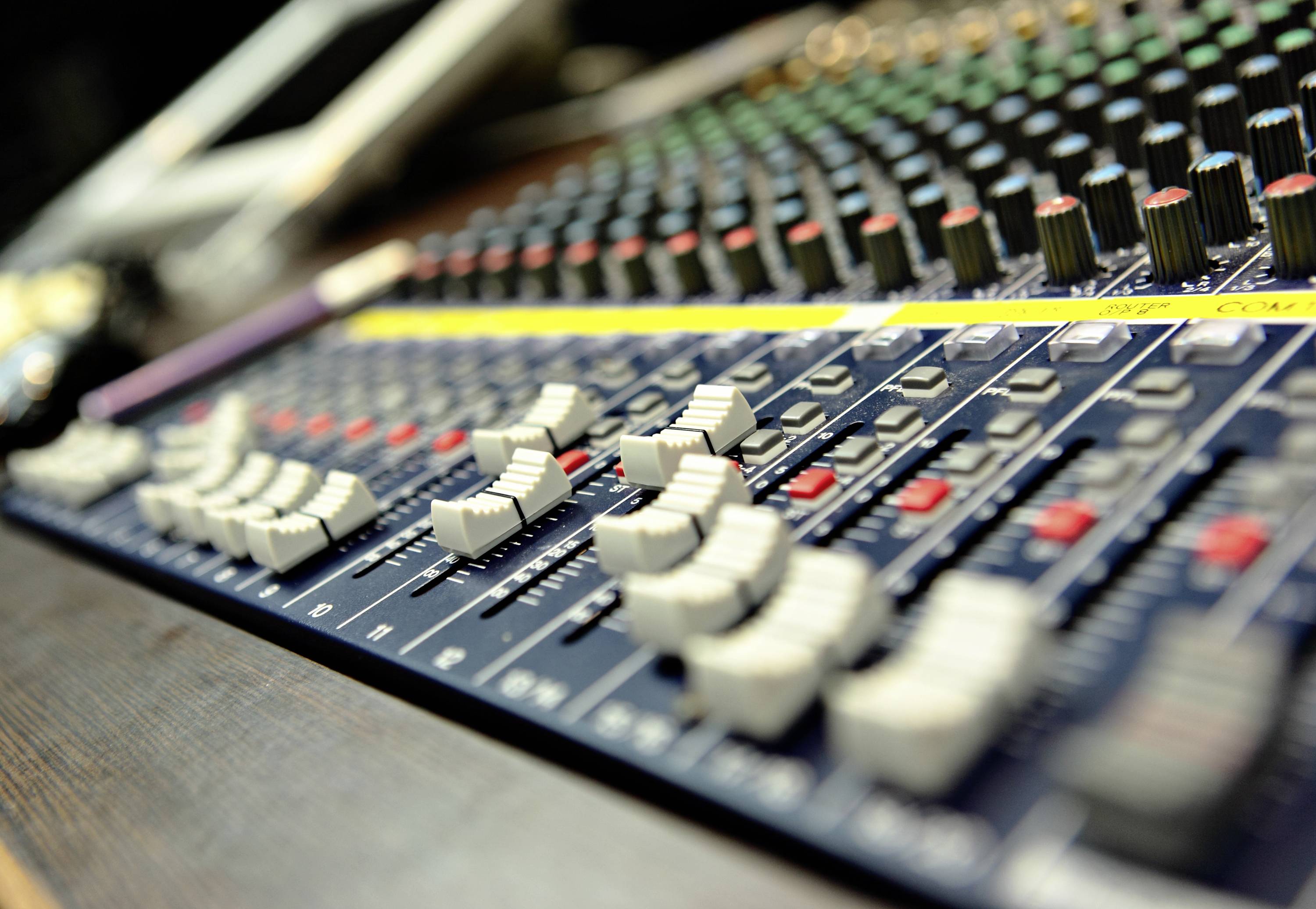 Mixer audio con numerosi fader e manopole utilizzati per controllare i livelli audio e le tonalità in studi di registrazione o durante eventi.