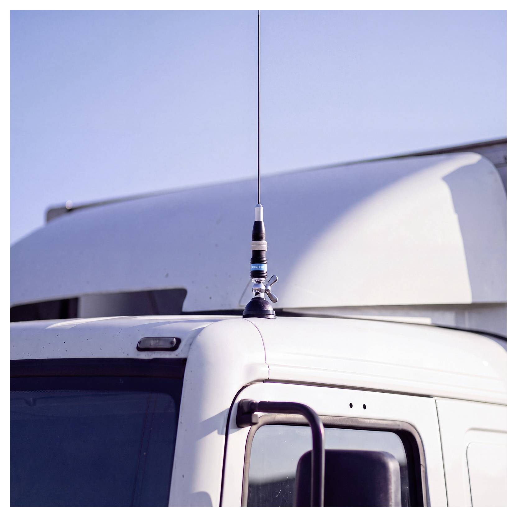 Primo piano della cabina di un camion bianco con un'antenna verticale montata sul tetto su un cielo limpido.