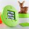 Vano batteria di un dispositivo di plastica verde, aperto. Dietro di esso, figura sfocata di un cervo in plastica.