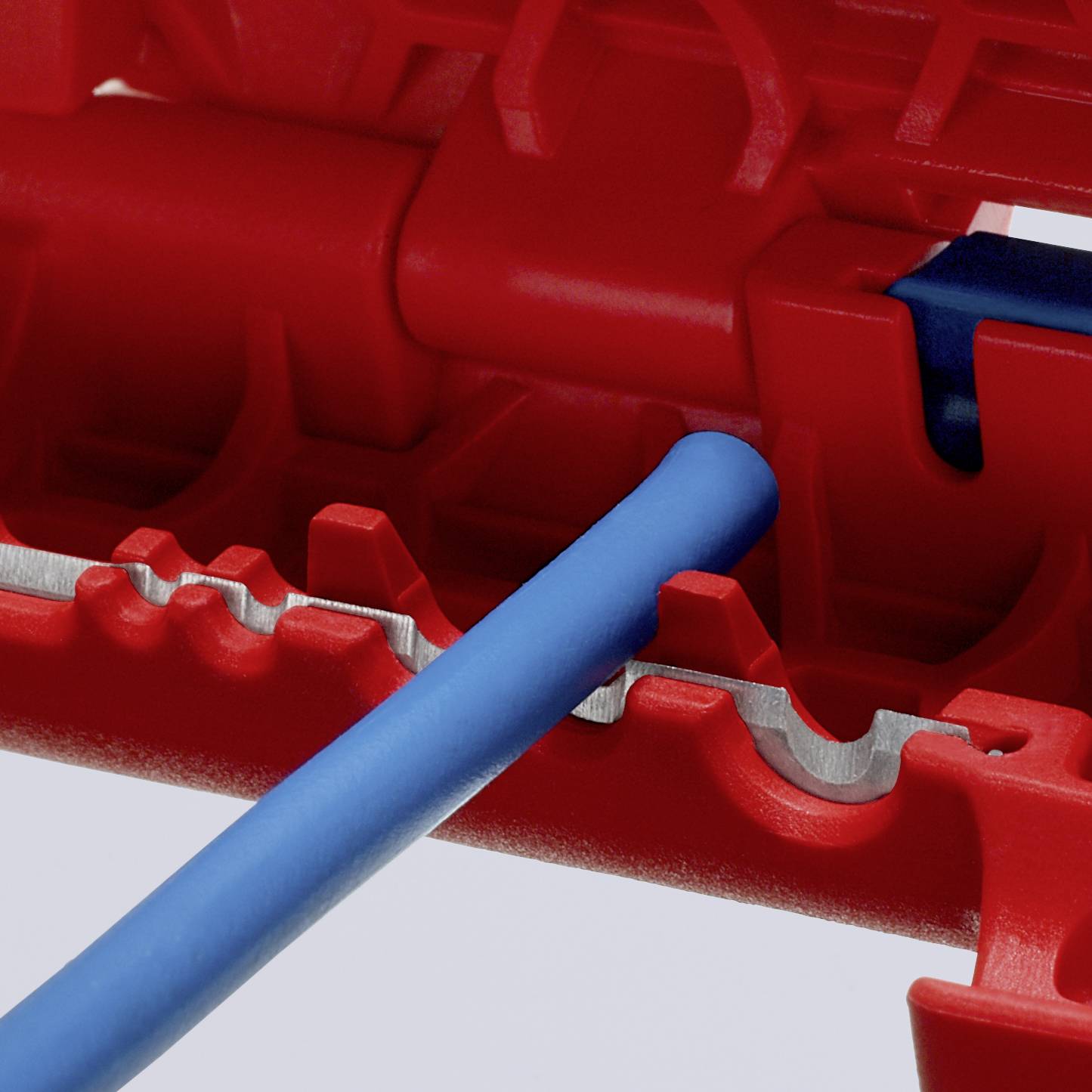 Un cavo blu viene inserito in una morsa rossa, la morsa ha aperture dentellate per un fissaggio sicuro del cavo.