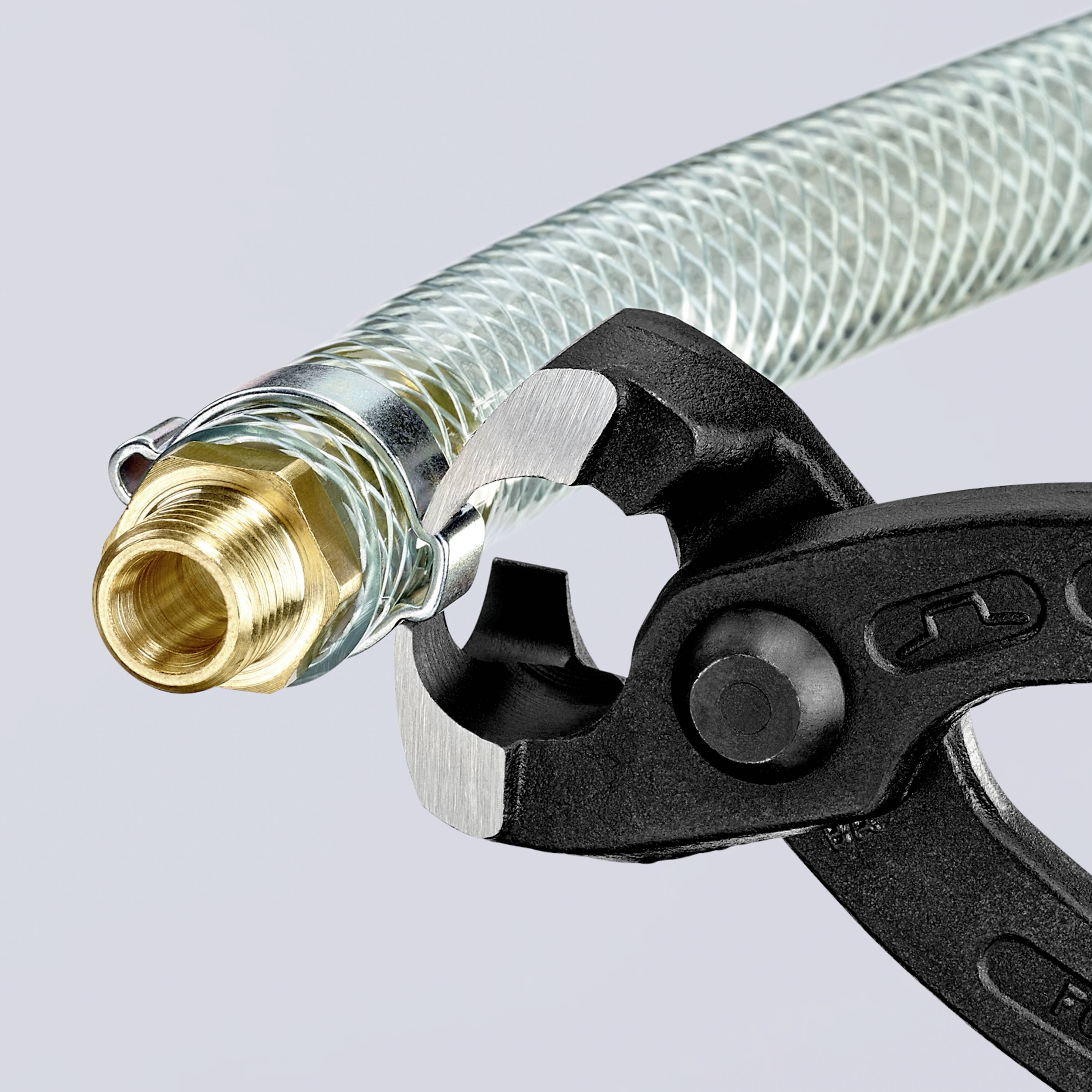 Un tubo dell'acqua con copertura in rete metallica viene tenuto da una pinza regolabile, mostrando lavori di installazione.