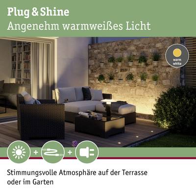 'Divano con cuscini su terrazza illuminata di notte, circondato da piante su un muro di pietra. Testo: Atmosfera in giardino.'
